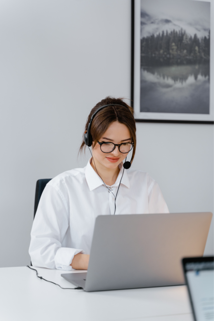 Sales agent wearing a headset, taking a customer call while on a computer.